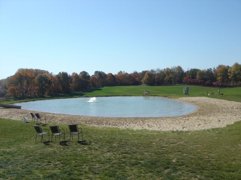 Pond located in Meadow Run Park with benches next to it